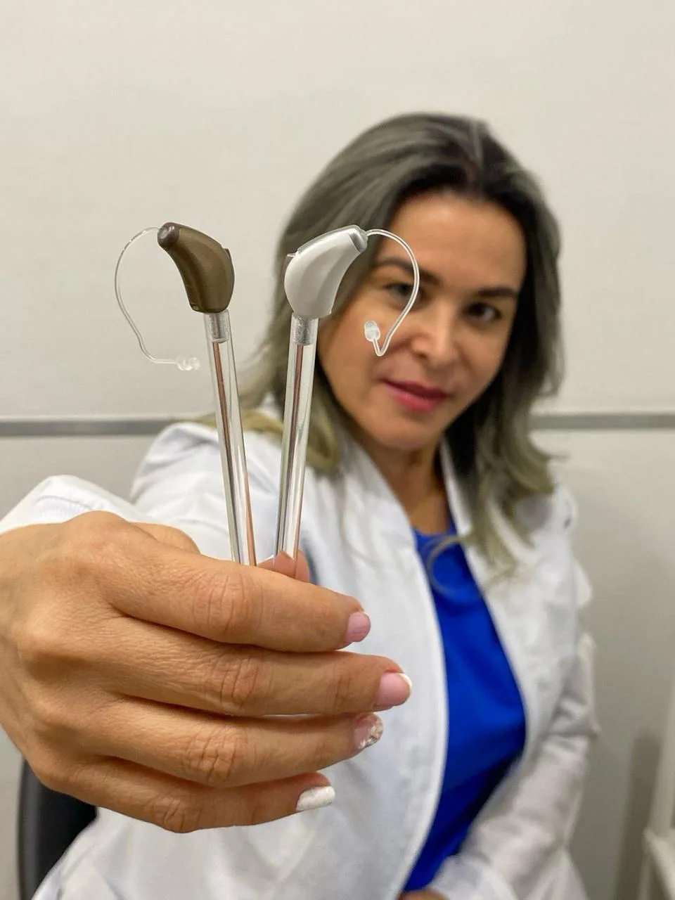 Especialista mostrando dos audífonos retroauriculares